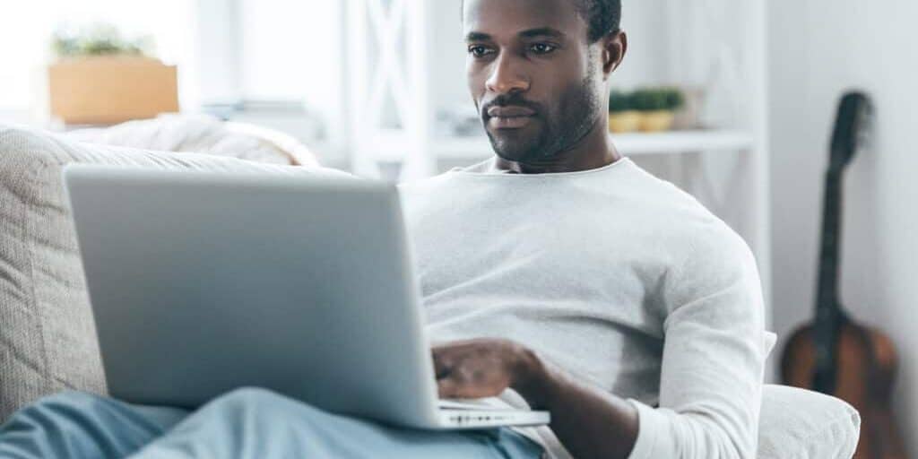 A man sitting on a couch using a laptop.