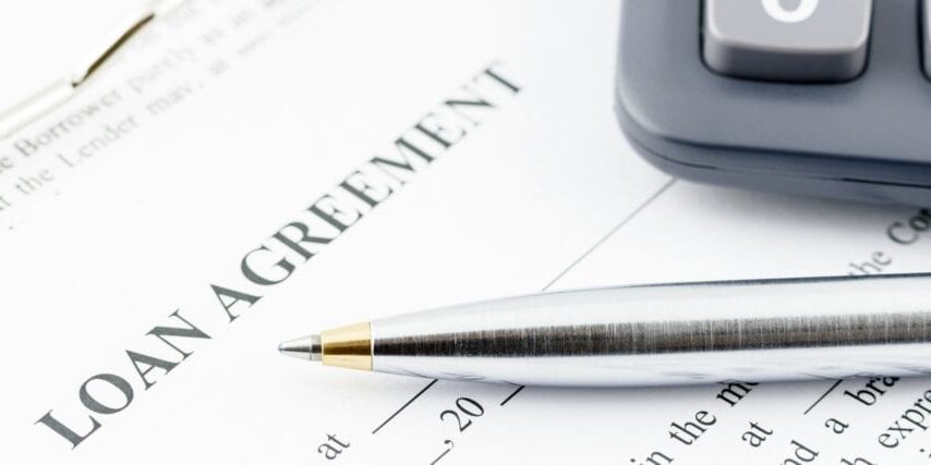 Blue ballpoint pen and a calculator on a loan agreement. Blue ballpoint pen and a calculator on a loan agreement, preparation for filling and signing a form on a clipboard.