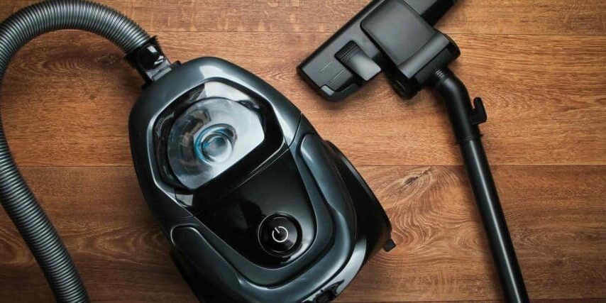 Vacuum cleaner on wooden floor. Top view. Cleaning concept.