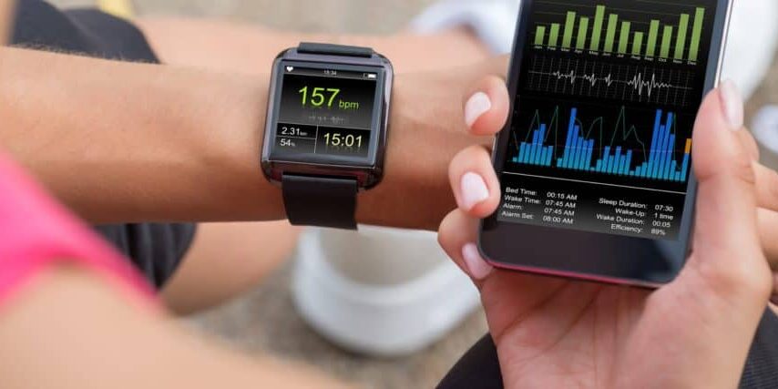 Female Runner Looking At Her Mobile And Smart Watch Heart Rate Monitor
