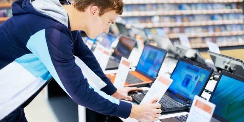 Young man in consumer electronic store checking the configuration in latest laptop computers